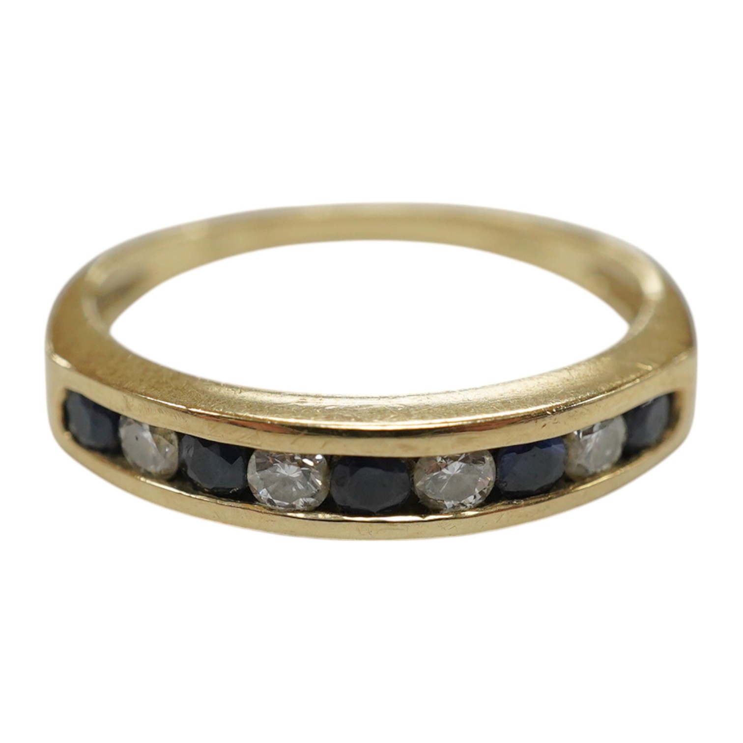 A modern 9ct gold and channel set sapphire and diamond set half hoop ring, size N/O, gross weight 2.2 grams. Condition - fair